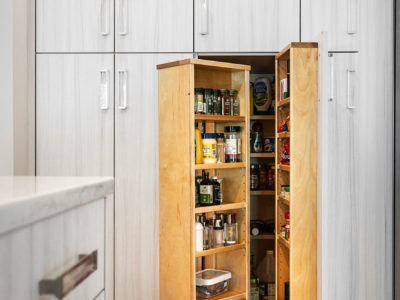 Open transitional white Tulsa kitchen design and remodel with tall pantry storage featuring clear hardware for condiments and dry food goods storage and wood flooring