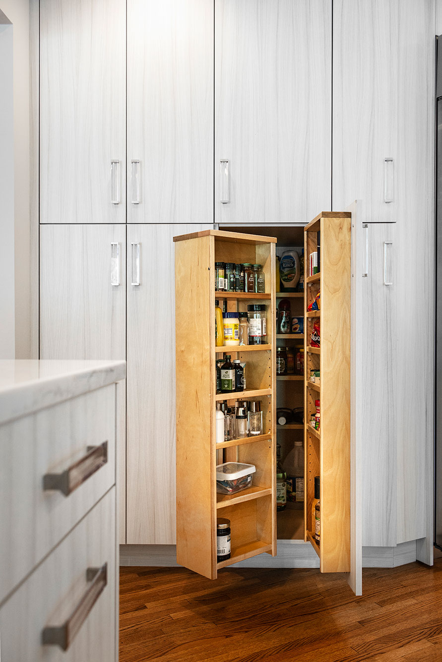 Open transitional white Tulsa kitchen design and remodel with tall pantry storage featuring clear hardware for condiments and dry food goods storage and wood flooring