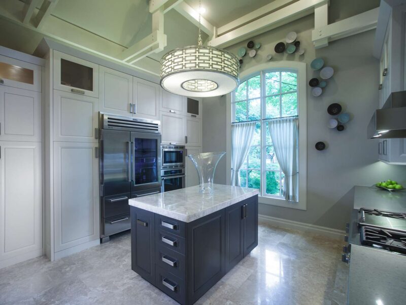 Tulsa kitchen remodel featuring tall pantry storage, island storage, Sub-Zero and Wolf stainless professional appliances, a decorative light, and a vaulted ceiling.