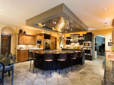 Open classic tuscan style kitchen featuring large island and functioning vent hood.