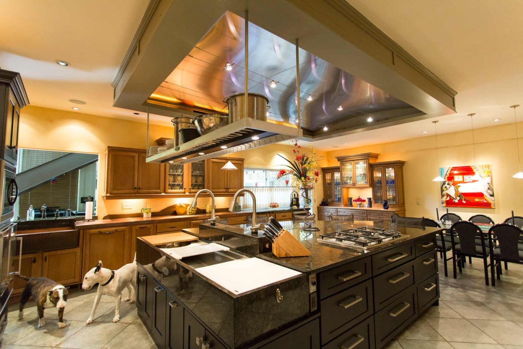 Classic tuscan style kitchen with large island featuring pullout storage, Galley Workstation kitchen sink and functioning vent hood.