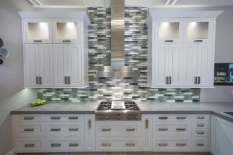 Tulsa kitchen remodel featuring a Thermador professional gas rangetop, a stainless steel canopy vent hood, a decorative subway tile backsplash, and white cabinet storage.