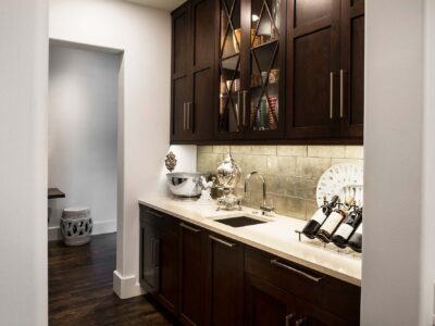 Tulsa kitchen remodel with decorative tile backsplash, bar sink, quartz counters, rich brown base and wall cabinet storage with glass front inserts