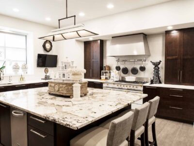 Tulsa kitchen remodel with quartzite counter-top on the island with seating, rich brown base cabinet storage, decorative pendant lighting and Lacanche french range