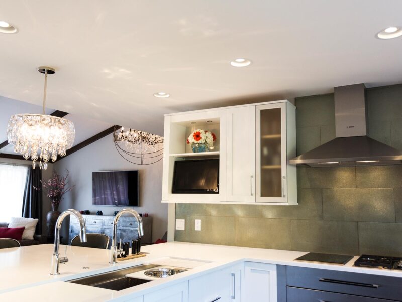 Tulsa kitchen remodel featuring a kitchen with base cabinet storage, a peninsula with a Galley sink workstation, a pendant light, quartz counters, wall cabinet storage, Bosch stainless steel appliances, a subway tile backsplash, and a vent hood.