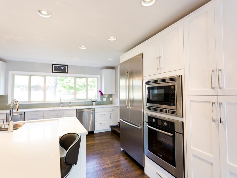 Tulsa kitchen remodel featuring a functional kitchen with tall storage, white cabinet storage, quartz counters, a Bosch French door refrigerator and freezer, a wall microwave and oven, and a tall pantry.
