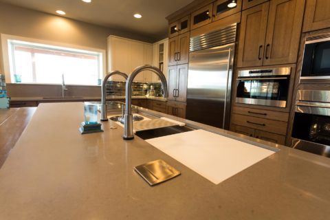 Tulsa kitchen design and remodel featuring a kitchen island with a Galley Workstation, pop-up outlets, quartz counters, Sub-Zero and Wolf appliances, and tall pantry storage.