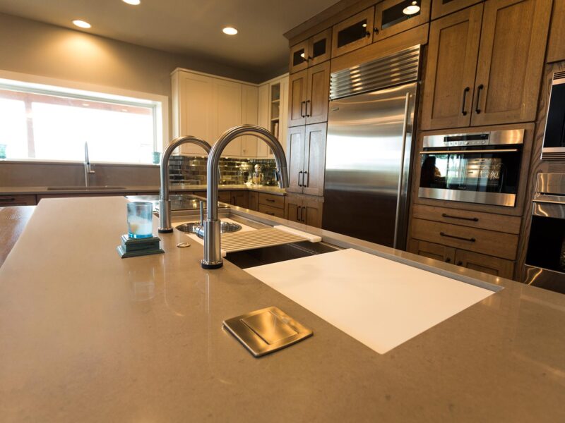 Tulsa kitchen design and remodel featuring a kitchen island with a Galley Workstation, pop-up outlets, quartz counters, Sub-Zero and Wolf appliances, and tall pantry storage.