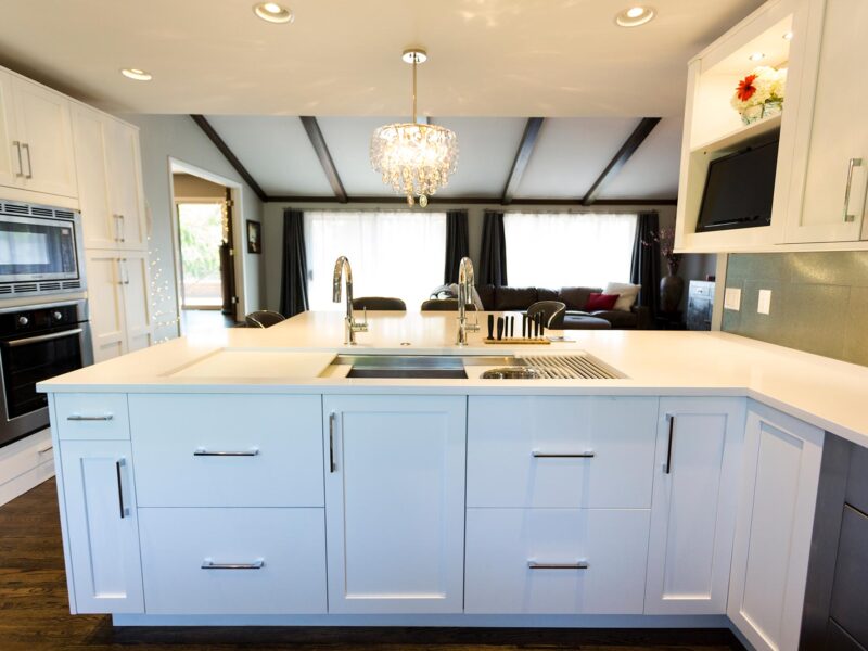 Tulsa kitchen design featuring a peninsula with storage, quartz counters, a Galley Workstation, white base cabinet storage, wood floors, a pendant light, and a Bosch French door refrigerator and freezer with a wall microwave and oven.
