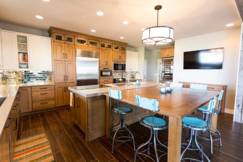 Tulsa kitchen design and remodel featuring a large ranch kitchen with an island, seating, a pendant light, cabinet storage, wood floors, and a tall wine refrigerator.