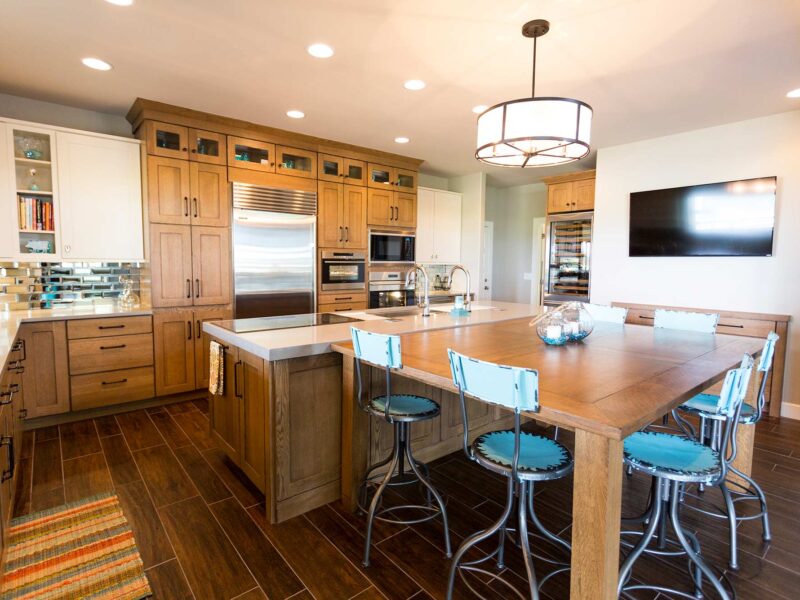 Tulsa kitchen design and remodel featuring a large ranch kitchen with an island, seating, a pendant light, cabinet storage, wood floors, and a tall wine refrigerator.