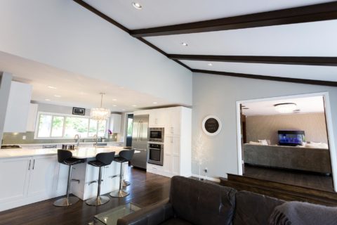 Tulsa kitchen remodel featuring an open white kitchen design with white cabinets, peninsula seating, a pendant light, Bosch appliances, tall storage, and a vaulted ceiling.