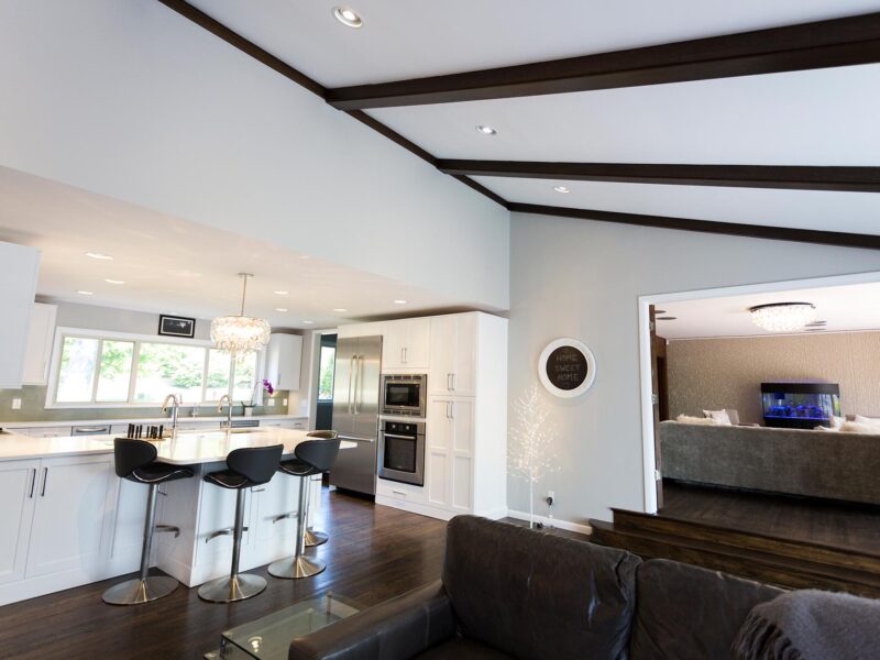 Tulsa kitchen remodel featuring an open white kitchen design with white cabinets, peninsula seating, a pendant light, Bosch appliances, tall storage, and a vaulted ceiling.