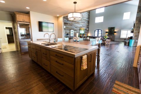 Tulsa kitchen remodel featuring a ranch kitchen with island storage, a Galley Workstation, a Wolf induction cooktop, a Sub-Zero tall wine refrigerator, wood floors, and island pendants.