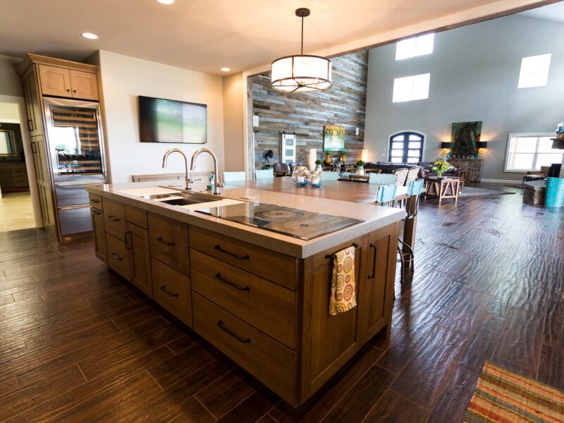 Tulsa kitchen remodel featuring a ranch kitchen with island storage, a Galley Workstation, a Wolf induction cooktop, a Sub-Zero tall wine refrigerator, wood floors, and island pendants.