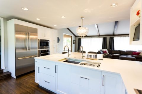 Tulsa kitchen remodel featuring tall pantry storage, a Bosch French door refrigerator and freezer, a wall microwave oven, peninsula storage with a Galley Workstation, a pendant light, and an adjacent living room.