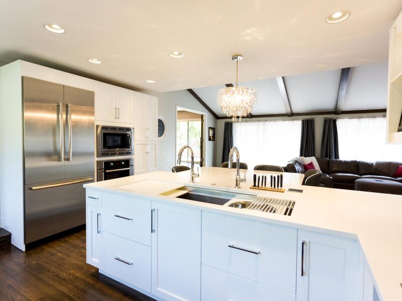 Tulsa kitchen remodel featuring tall pantry storage, a Bosch French door refrigerator and freezer, a wall microwave oven, peninsula storage with a Galley Workstation, a pendant light, and an adjacent living room.