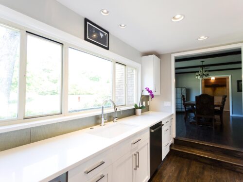 Tulsa kitchen design and remodel featuring a white kitchen with drawer storage, an undermount clean-up sink, a quartz countertop, a formal dining room entry, and wood floors.