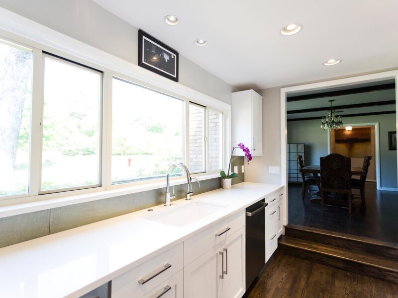 Tulsa kitchen design and remodel featuring a white kitchen with drawer storage, an undermount clean-up sink, a quartz countertop, a formal dining room entry, and wood floors.