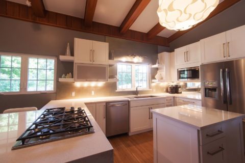 Tulsa kitchen remodel featuring an open white kitchen with vaulted ceilings, a peninsula with seating, open shelves, a stainless steel dishwasher and microwave, and a side-by-side refrigerator with a bottom freezer.