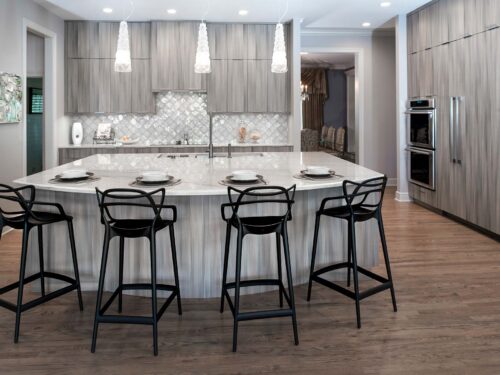 Tulsa kitchen remodel featuring a large kitchen island with pendant lighting, a Galley Workstation, Harmoni cabinets, refinished wood floors, and stainless steel appliances.