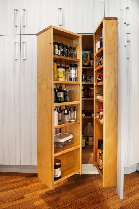 Tulsa kitchen remodel featuring a tall pantry cabinet with transparent hardware, organized condiment and dry food goods, and wood flooring.