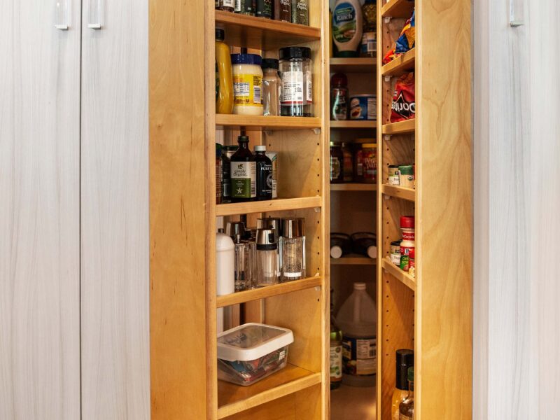 Tulsa kitchen remodel featuring a tall pantry cabinet with transparent hardware, organized condiment and dry food goods, and wood flooring.