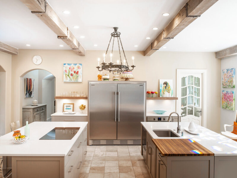 Tulsa kitchen remodel featuring two islands with base storage, pendant lights, an induction cooktop, a prep sink with a recessed cutting board, a full-size Frigidaire all-freezer and refrigerator, and open shelves over tile floors.