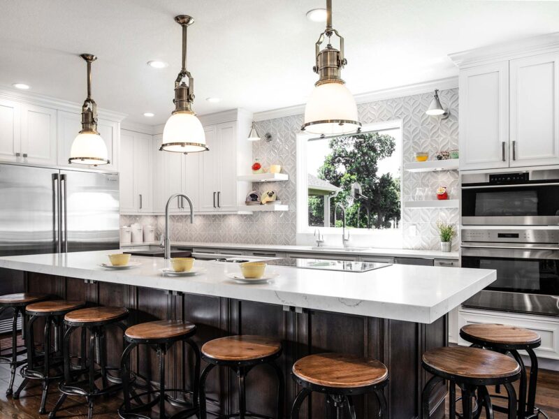 Tulsa kitchen design and remodel featuring a kitchen island with seating, an Electrolux full-size refrigerator and freezer, a Galley Workstation, Wolf ovens, a decorative tile backsplash, and pendant lighting.