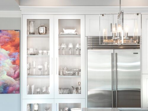 Tulsa kitchen remodel featuring a tall white pantry storage unit, a stainless steel Sub-Zero refrigerator and freezer, and a decorative pendant light.