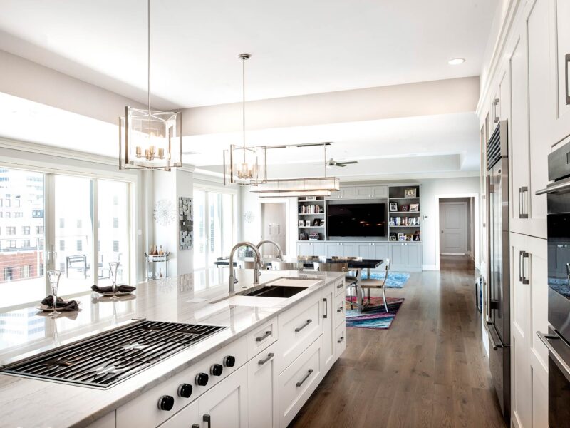 Tulsa penthouse kitchen featuring a large island, pendant lights, a Galley Workstation, and a Wolf gas cooktop, with adjacent dining, living, and entertainment room space.