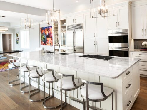 Tulsa penthouse kitchen design and remodel featuring wood floors, a large island, pendant lighting, a gas cooktop, a Galley Workstation, stainless steel appliances, and tall pantry storage.
