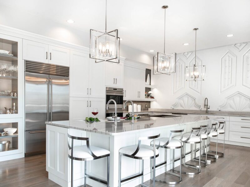 Tulsa kitchen remodel featuring a white kitchen island with seating, a Galley Workstation, a Wolf gas cooktop, a Sub-Zero refrigerator and freezer, Wolf double ovens, a clean-up sink, and wood floors.