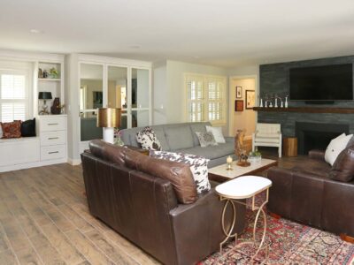 Designed and remodeled living room featuring a gray stone fireplace, wood mantle, and built-in storage. Tulsa living room design.