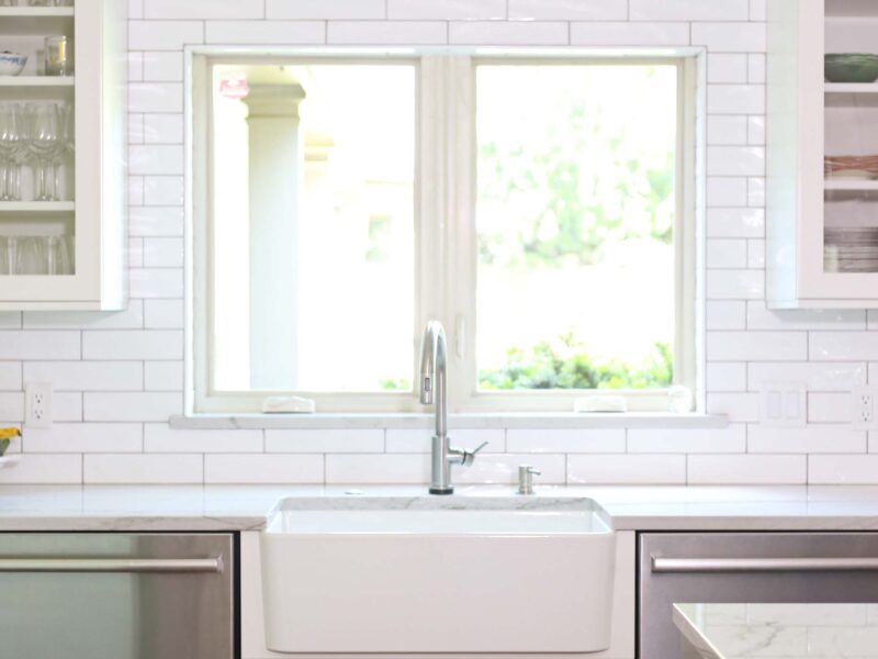 Tulsa kitchen remodel featuring a farmhouse kitchen sink, a stainless steel Monogram dishwasher, a subway tile backsplash, and extensive white kitchen cabinet storage.