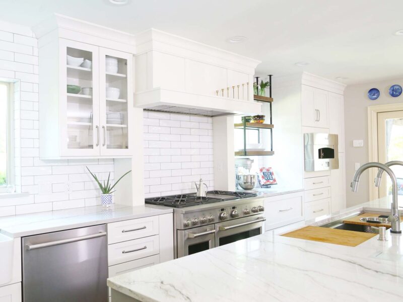 Tulsa kitchen design featuring a Galley Workstation, a stainless steel kitchen sink, a GE Monogram dishwasher, a gas range, a hearth pizza oven, and white cabinets.