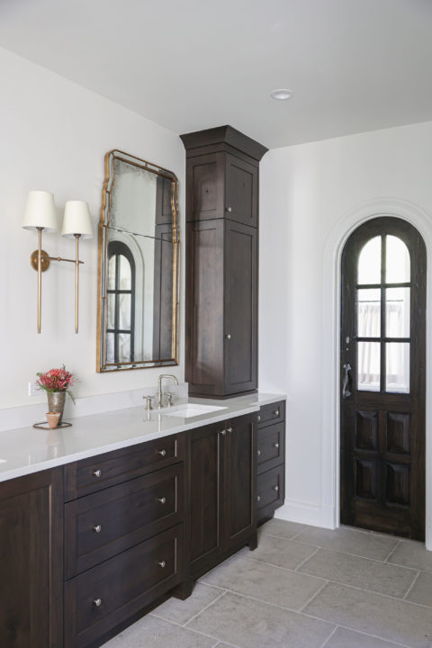 A beautiful Tulsa master bathroom remodel featuring a vanity with ample storage, crown molding, and elegant wall sconces.