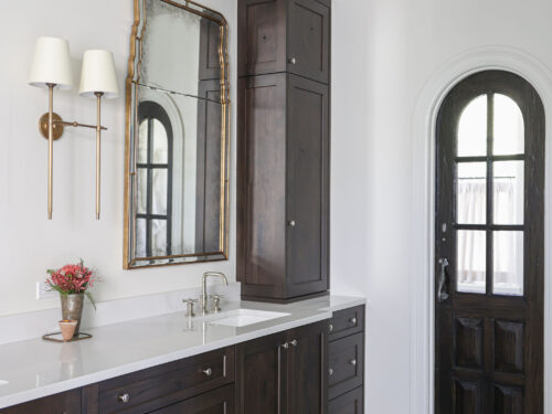 A beautiful Tulsa master bathroom remodel featuring a vanity with ample storage, crown molding, and elegant wall sconces.