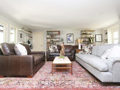 Open and spacious Tulsa living room remodel featuring white walls, ample seating, and decorative open shelving.