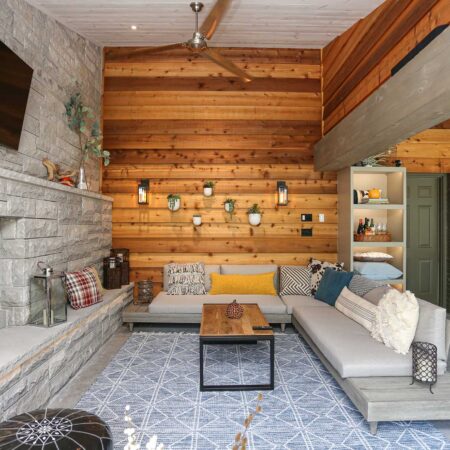 Spacious open-concept patio featuring stone wood-burning fireplace, comfortable lounge seating, and wall-mounted television in Tulsa design and remodel.