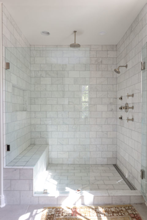 A stunning Tulsa master bathroom design and remodel featuring a walk-in shower with a rainfall shower head, a curb, a built-in shower bench, and classic subway tile.