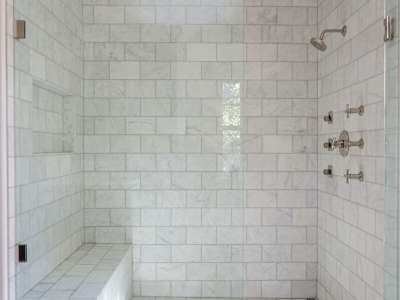 A stunning Tulsa master bathroom design and remodel featuring a walk-in shower with a rainfall shower head, a curb, a built-in shower bench, and classic subway tile.