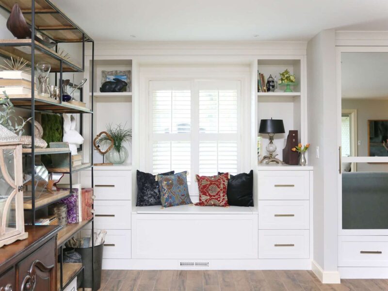 Modern white built-in seating with integrated storage and decorative shelving on wood flooring in Tulsa living room kitchen renovation.