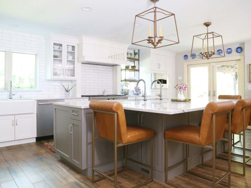 Tulsa kitchen remodel featuring white shaker perimeter cabinets, a slate shaker island with leather seating, white counters, and wood floors.