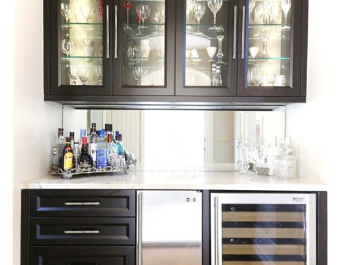 Tulsa kitchen design and remodel featuring a bar space with drawer storage, under counter stainless steel ice, wine, and beverage refrigerators, and a sleek mirror backsplash.