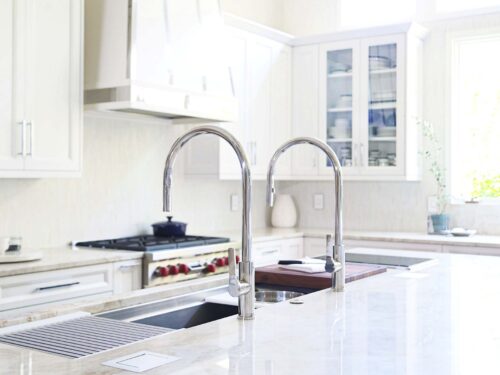 Tulsa kitchen remodel featuring a large island with a Galley Workstation, modern tap faucets, a Wolf induction cooktop, and extensive white cabinet storage.