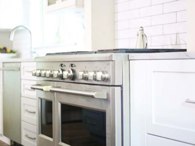 Spacious Tulsa kitchen remodel with GE Cafe gas range and vent hood above backed by subway tile backsplash