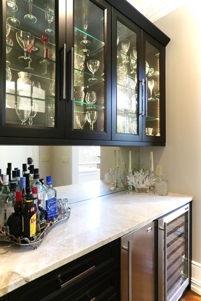 Tulsa kitchen bar space with rich dark brown cabinets, under counter stainless Sub-Zero ice and wine/beverage refrigerator and mirror backsplash