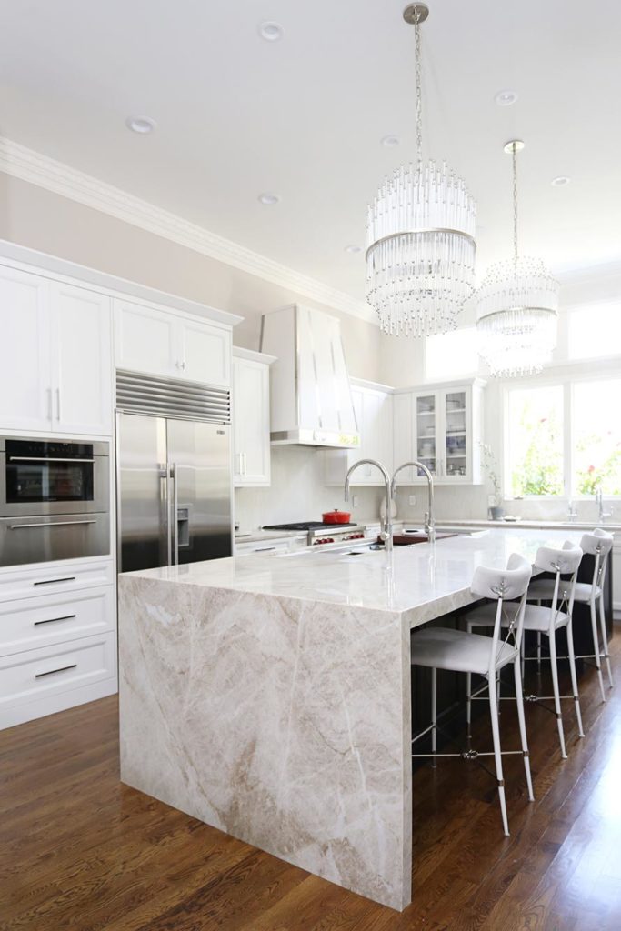 Expansive Tulsa kitchen with large island seating and waterfall edge counter-top, wood floors and stainless Sub-Zero Wolf appliances