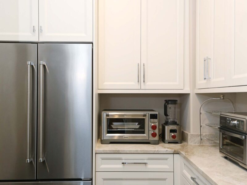 Tulsa kitchen design and remodel featuring a walk-in pantry with ample storage space, a stainless steel french door refrigerator and freezer, and base and wall cabinet storage with a countertop and a toaster oven.